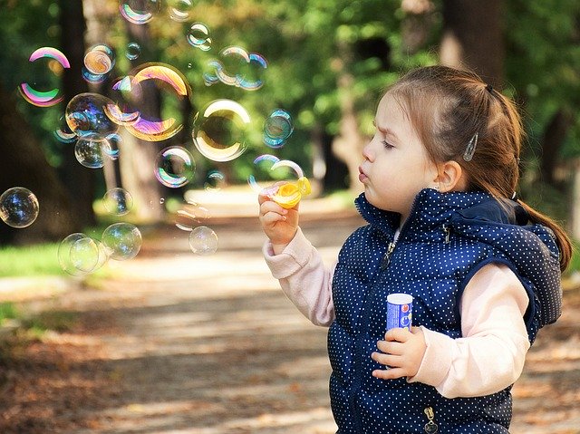 Malé dievča v parku robí bubliny